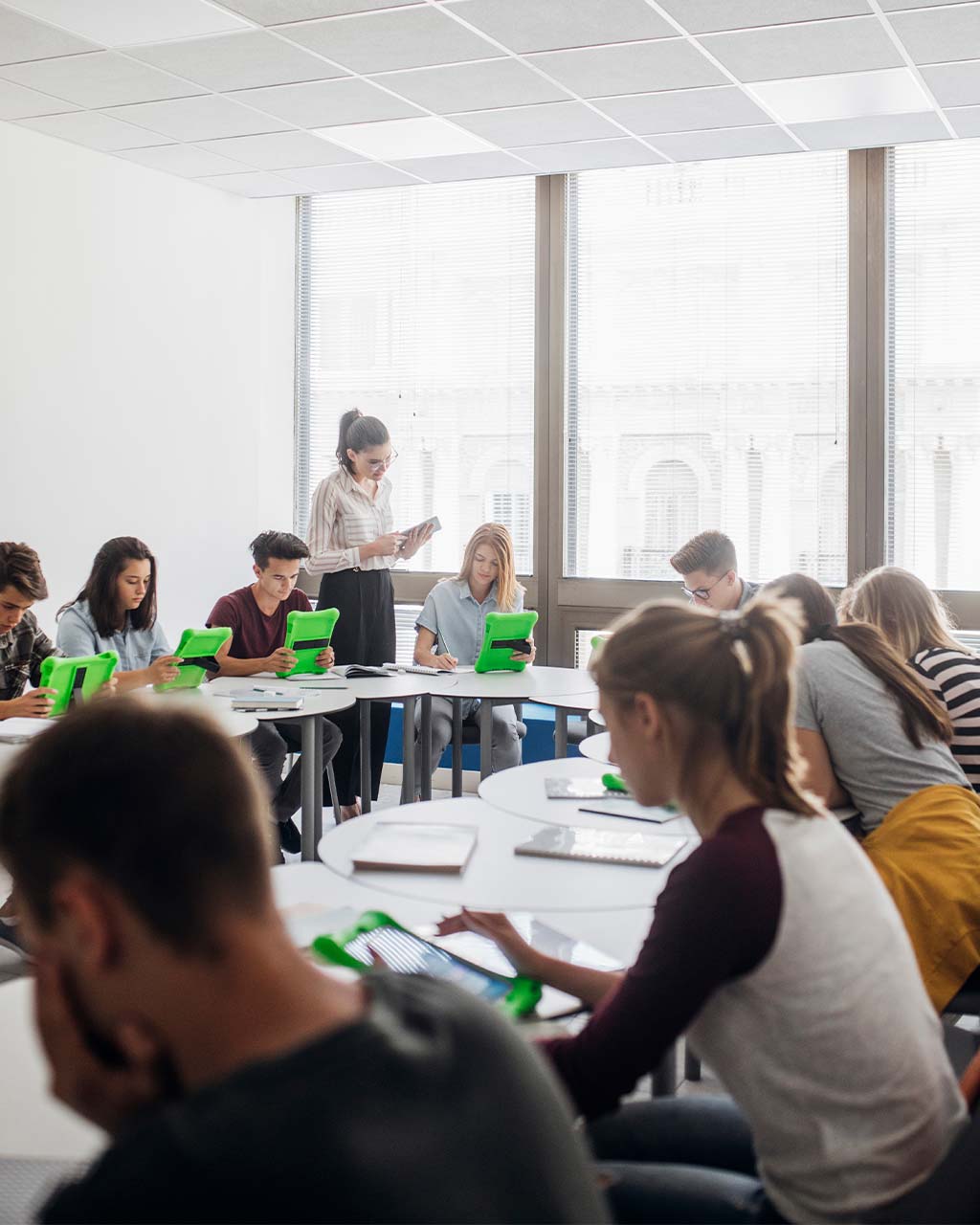 Lehrerin begleitet Schülerinnen und Schüler beim Lernen mit Tablets im Klassenraum – barrierefreie Lernplattformen und e-Learning-Inhalte für Hochschulen und Bildungsanbieter nach BFSG und BITV 2.0