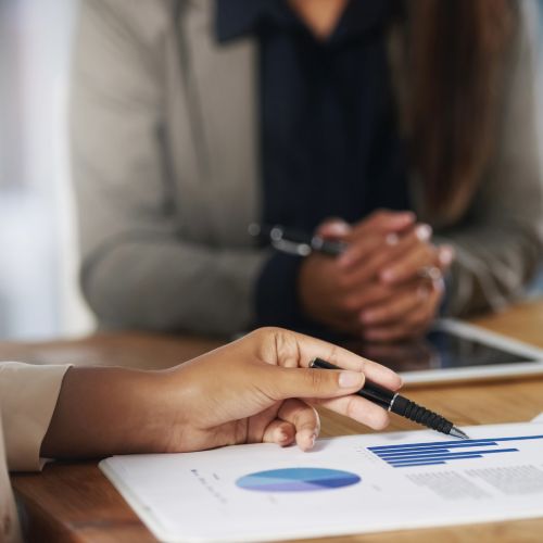 Hand zeigt mit Stift auf ein Budgetdiagramm im Beratungsgespräch – Kosten einer barrierefreien Website: realistische Budgets und Fördermöglichkeiten für BFSG-konforme Umsetzung nach WCAG 2.2
