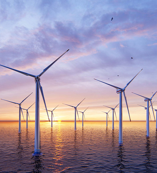 Offshore-Windpark mit Windrädern im Meer bei Sonnenuntergang – erneuerbare Energie als Teil der digitalen Grundversorgung nach BFSG