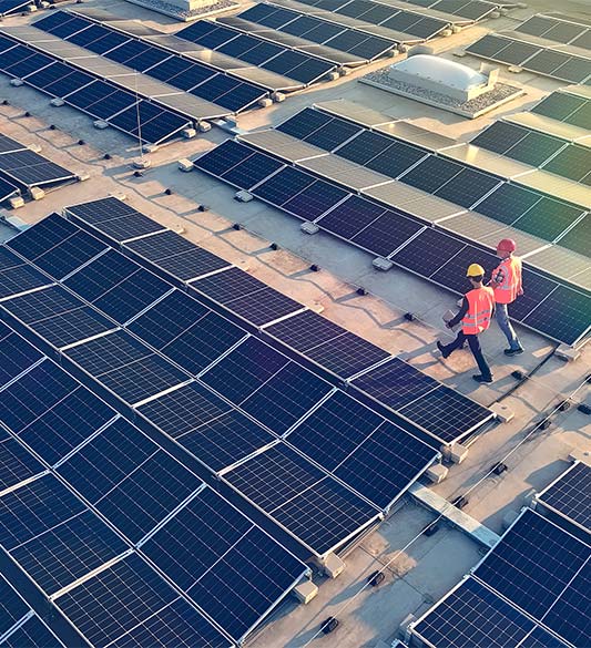 Zwei Techniker in Sicherheitsausrüstung prüfen eine gewerbliche Photovoltaikanlage auf einem Flachdach – barrierefreie Kundenportale für Energieversorger und Stadtwerke