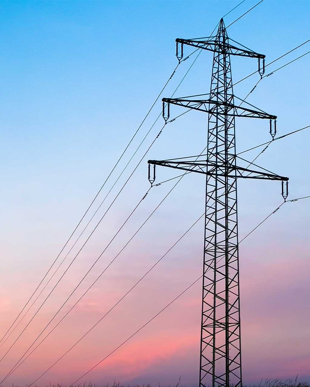 Hochspannungsmast mit Stromleitungen vor rosafarbenem Abendhimmel – digitale Barrierefreiheit in Self-Service-Strecken und Kundenportalen für Energieversorger und Stadtwerke nach BFSG