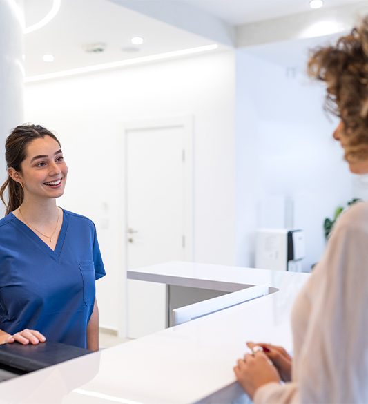 Medizinische Fachkraft am Empfang einer Klinik im Gespräch mit einer Patientin – digitale Barrierefreiheit für Krankenkassen und Gesundheitseinrichtungen nach BFSG