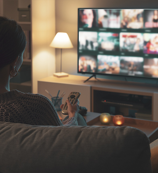 Person auf dem Sofa schaut eine Streaming-Plattform auf einem Smart-TV – barrierefreie Videoplayer und Untertitel für Streaming-Anbieter nach BFSG und WCAG 2.2