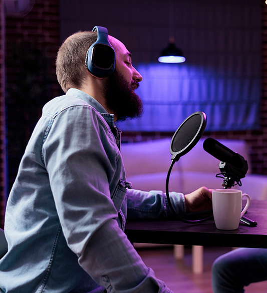 Podcaster mit Kopfhörern spricht in ein Studiomikrofon – barrierefreie Audio- und Videoinhalte mit Transkript für Medienanbieter nach BFSG und BITV 2.0