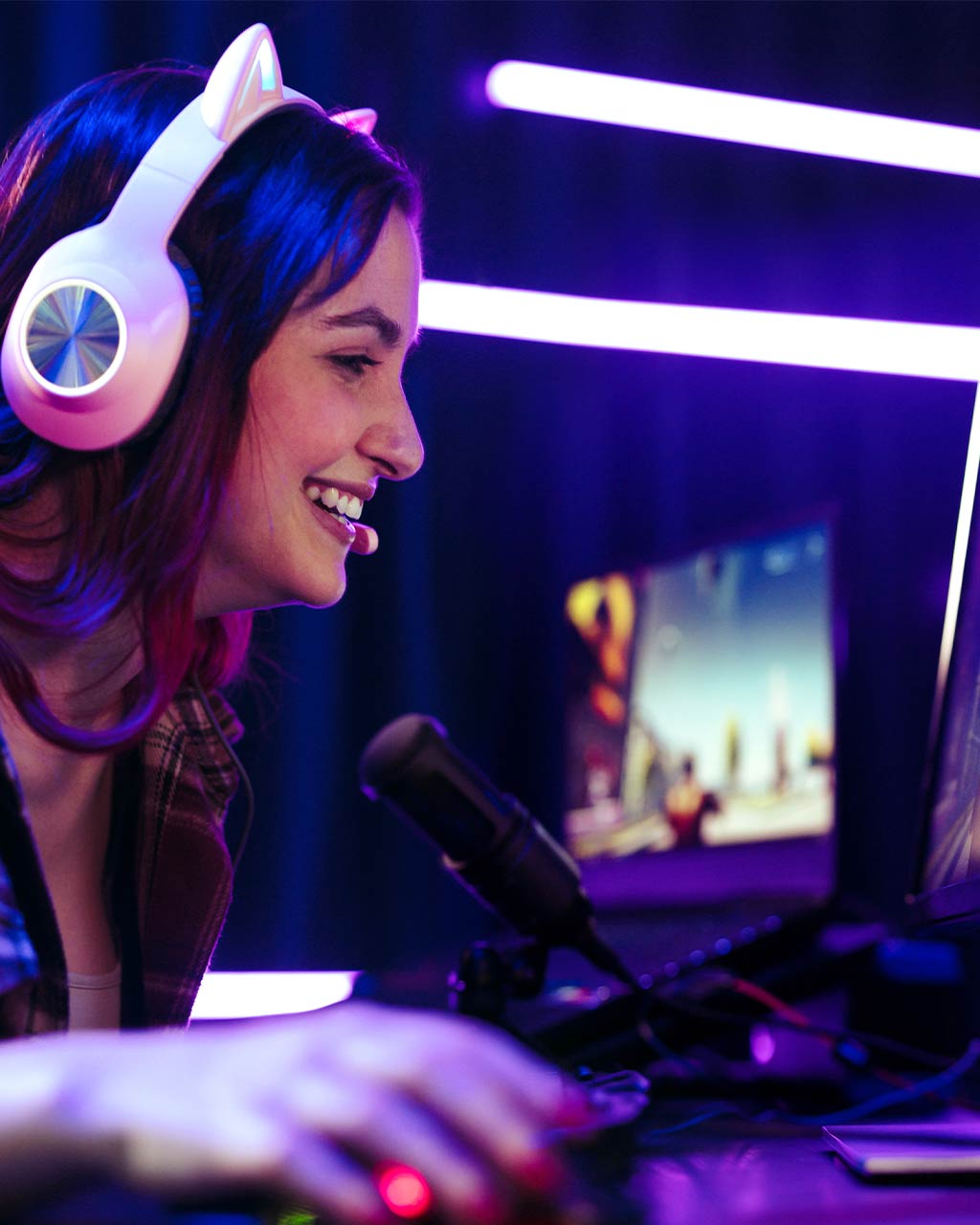 Junge Frau mit beleuchtetem Gaming-Headset lächelt vor einem PC-Monitor – unzugängliche Videoplayer und fehlende Untertitel als Barrierefreiheits-Problem für Streaming-Anbieter und Medienplattformen nach BFSG und WCAG 2.2