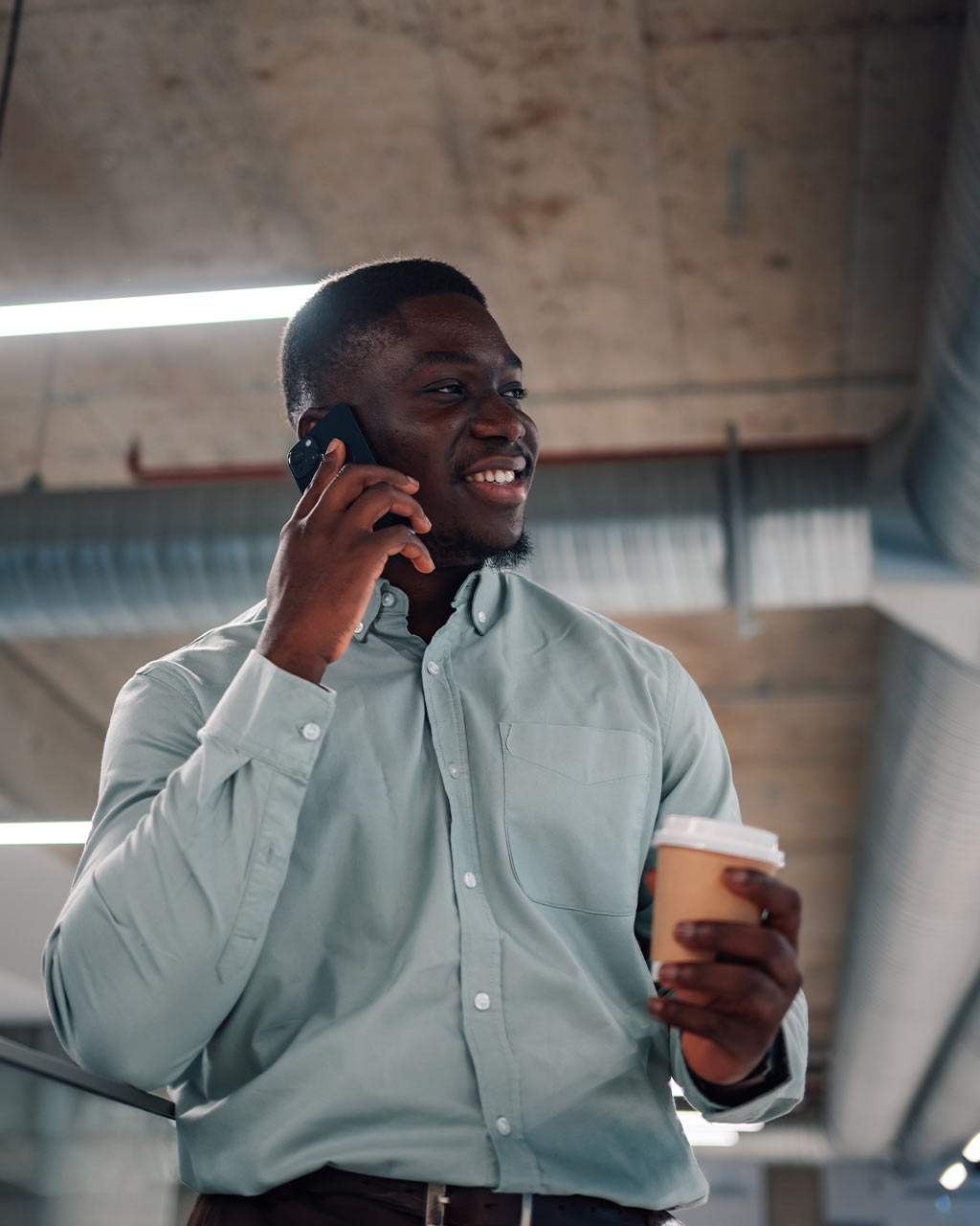 Mann telefoniert lächelnd mit dem Smartphone und hält einen Coffee-to-go – unzugängliche Tarif-Konfiguratoren und Self-Service-Portale als Barrierefreiheits-Problem für Telekommunikationsanbieter nach BFSG und WCAG 2.2