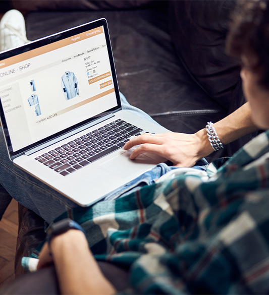 Mann sitzt auf dem Sofa und browst in einem Online-Shop für Kleidung auf seinem Laptop – barrierefreie Produktseiten und Navigation für E-Commerce-Plattformen nach WCAG 2.2