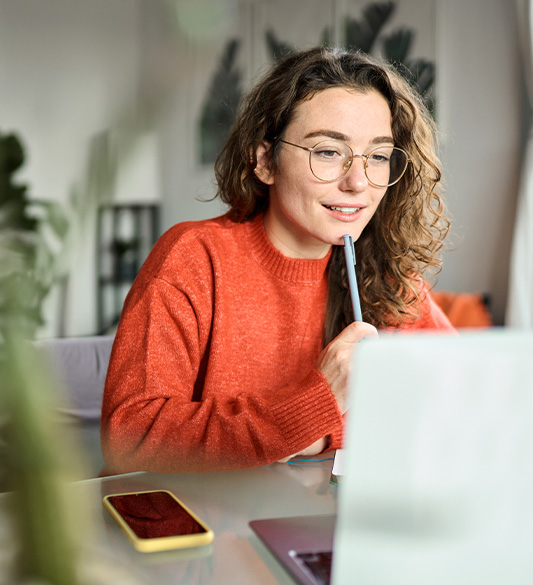 Studentin lernt konzentriert am Laptop und macht sich Notizen auf einer barrierefreien Lernplattform