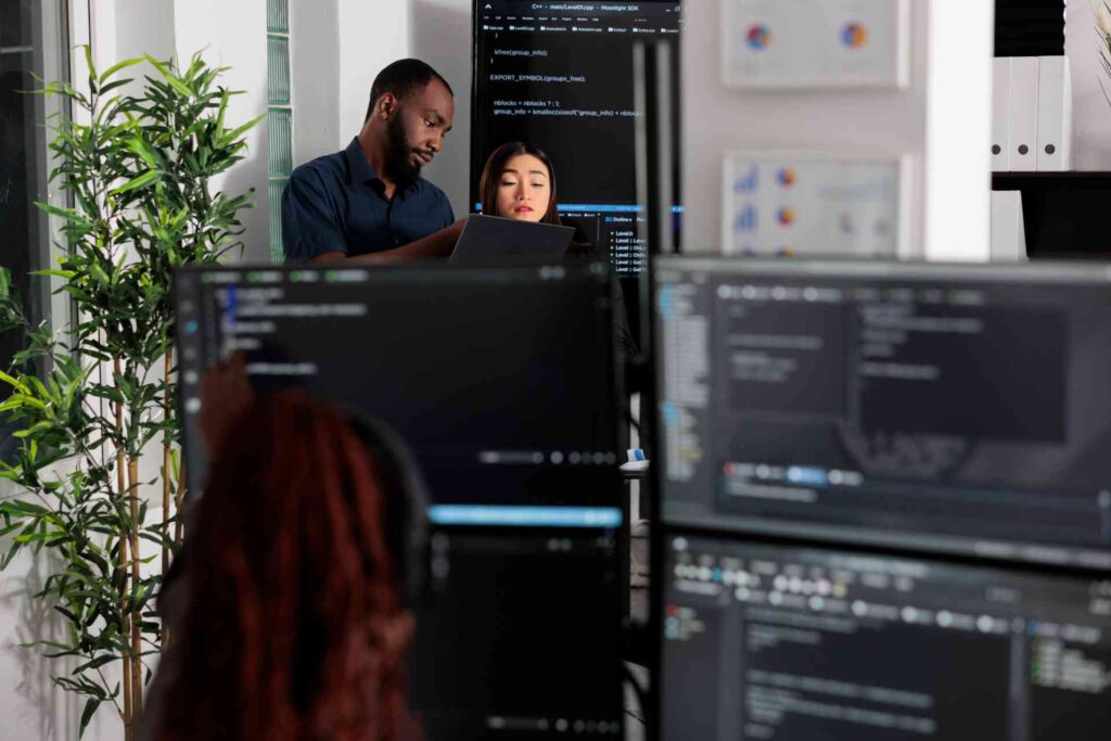 Team arbeitet konzentriert an mehreren Monitoren mit Code und Diagrammen – barrierefreie Geschäftsberichte und Behörden-PDFs: PDF/UA-Konvertierung von Altbeständen nach BFSG und WCAG 2.2