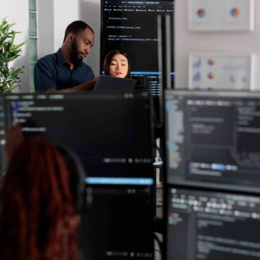 Team arbeitet konzentriert an mehreren Monitoren mit Code und Diagrammen – barrierefreie Geschäftsberichte und Behörden-PDFs: PDF/UA-Konvertierung von Altbeständen nach BFSG und WCAG 2.2