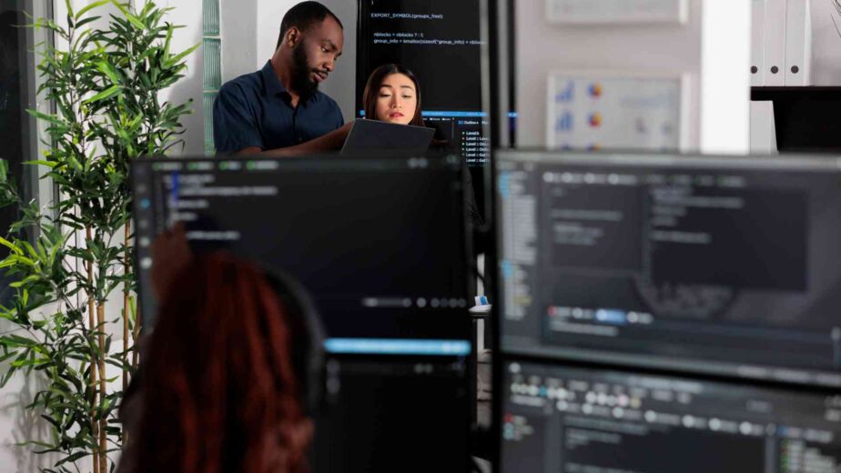 Team arbeitet konzentriert an mehreren Monitoren mit Code und Diagrammen – barrierefreie Geschäftsberichte und Behörden-PDFs: PDF/UA-Konvertierung von Altbeständen nach BFSG und WCAG 2.2