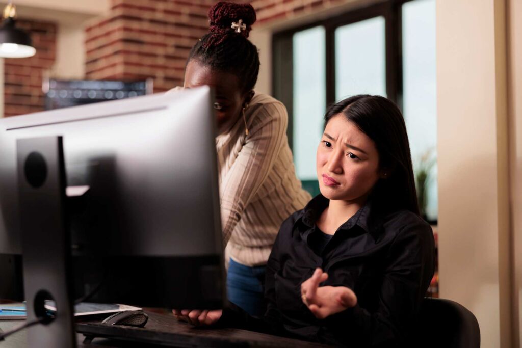 Frau gestikuliert frustriert vor einem großen Computerbildschirm – wie echte Nutzer Websites mit Screenreadern wie JAWS, NVDA und VoiceOver erleben und wo digitale Barrieren nach WCAG 2.2 entstehen