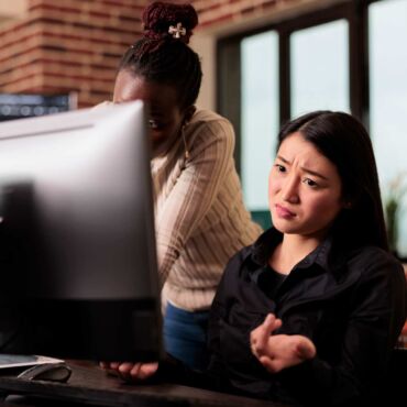 Frau gestikuliert frustriert vor einem großen Computerbildschirm – wie echte Nutzer Websites mit Screenreadern wie JAWS, NVDA und VoiceOver erleben und wo digitale Barrieren nach WCAG 2.2 entstehen