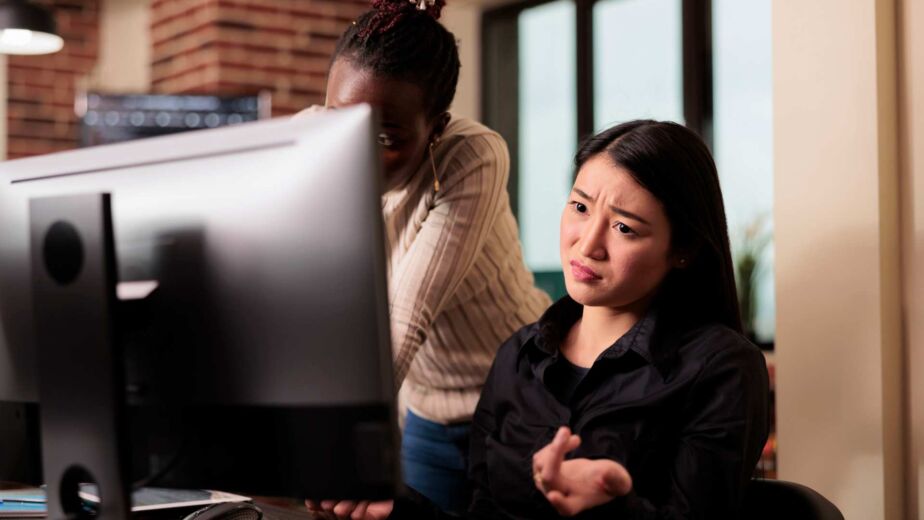 Frau gestikuliert frustriert vor einem großen Computerbildschirm – wie echte Nutzer Websites mit Screenreadern wie JAWS, NVDA und VoiceOver erleben und wo digitale Barrieren nach WCAG 2.2 entstehen