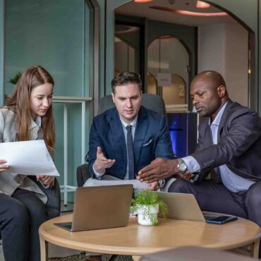 Drei Personen in Business-Kleidung besprechen ein Dokument mit Laptop – European Accessibility Act: Was der EAA und das BFSG für Unternehmen im DACH-Raum rechtlich bedeuten nach WCAG 2.2 und EN 301 549