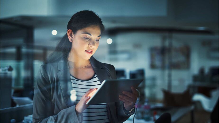 Frau liest konzentriert ein Dokument auf einem Tablet im abgedunkelten Büro – PDF barrierefrei machen: Schritt-für-Schritt-Anleitung für PDF/UA-konforme und rechtssichere Dokumente nach BFSG und WCAG 2.2