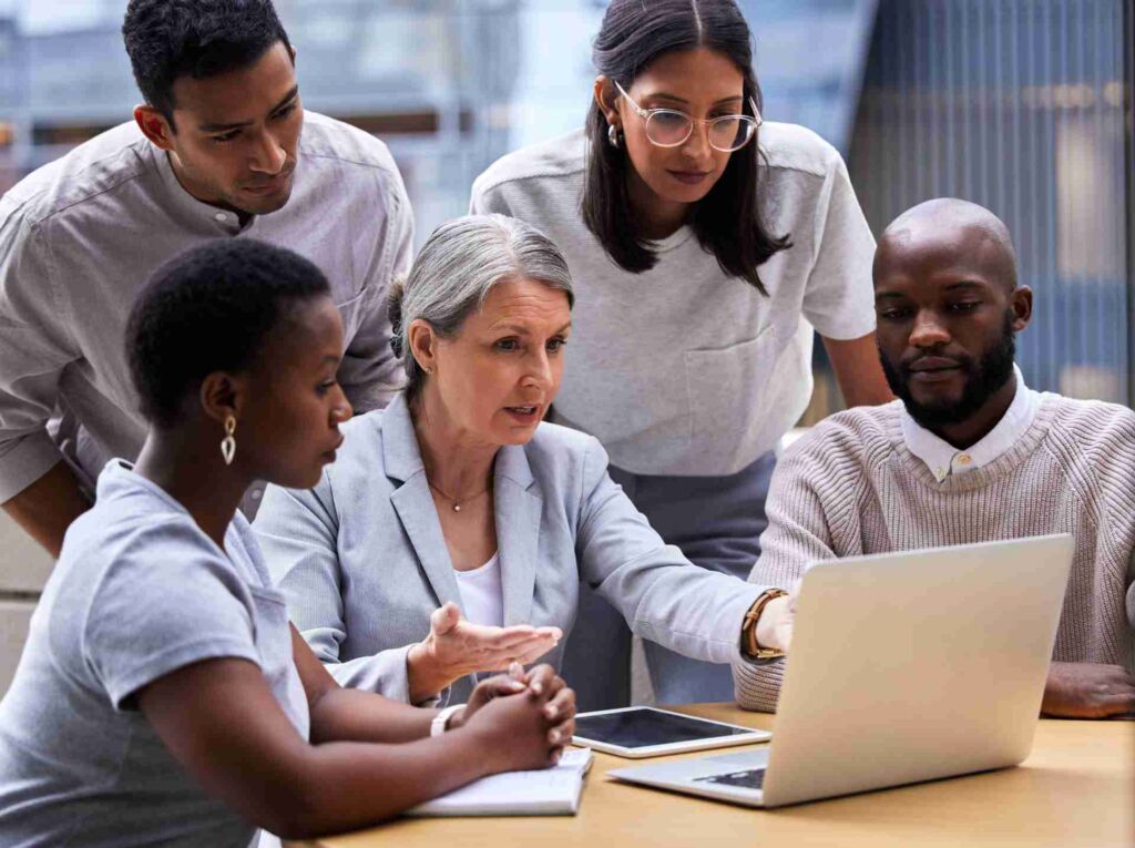 Diverse Gruppe von vier Personen analysiert konzentriert gemeinsam einen Laptop-Bildschirm – barrierefreies PDF erstellen: PDF/UA und Matterhorn-Protokoll verständlich erklärt nach BFSG und WCAG 2.2