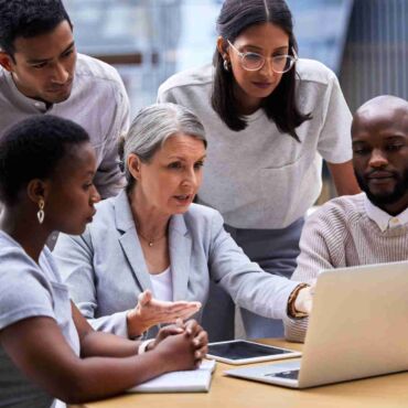Diverse Gruppe von vier Personen analysiert konzentriert gemeinsam einen Laptop-Bildschirm – barrierefreies PDF erstellen: PDF/UA und Matterhorn-Protokoll verständlich erklärt nach BFSG und WCAG 2.2
