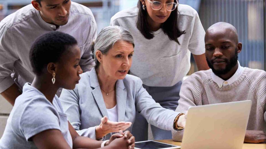Diverse Gruppe von vier Personen analysiert konzentriert gemeinsam einen Laptop-Bildschirm – barrierefreies PDF erstellen: PDF/UA und Matterhorn-Protokoll verständlich erklärt nach BFSG und WCAG 2.2