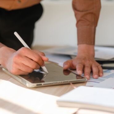 Person arbeitet mit Stylus auf einem Tablet neben Checklisten und Auswertungsunterlagen – Barrierefreiheit testen: Methoden, Tools und Checkliste für den Einstieg nach WCAG 2.2 und BFSG