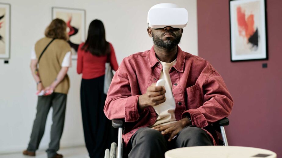 Mann im Rollstuhl trägt eine VR-Brille in einem modernen Ausstellungsraum – Was bedeutet digitale Barrierefreiheit? Definition, WCAG 2.2 und der Business-Case nach BFSG