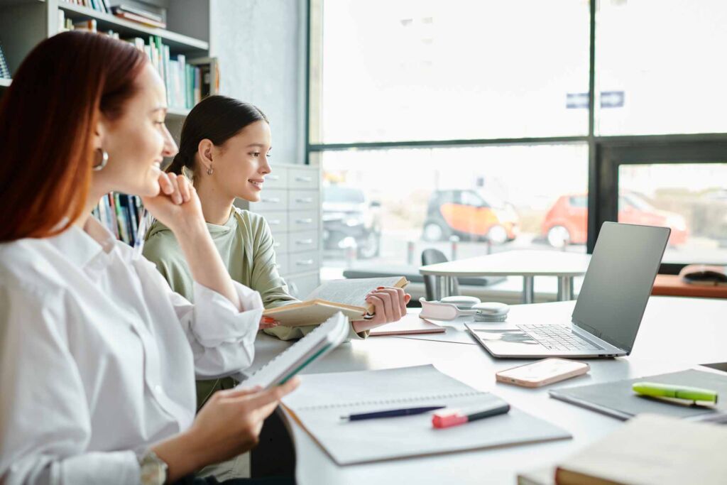 Zwei Frauen arbeiten konzentriert mit Unterlagen und Laptop am Tisch – Erklärung zur Barrierefreiheit: Pflichtinhalte, Aufbau und häufige Fehler bei der BFSG- und BITV-2.0-konformen Konformitätserklärung