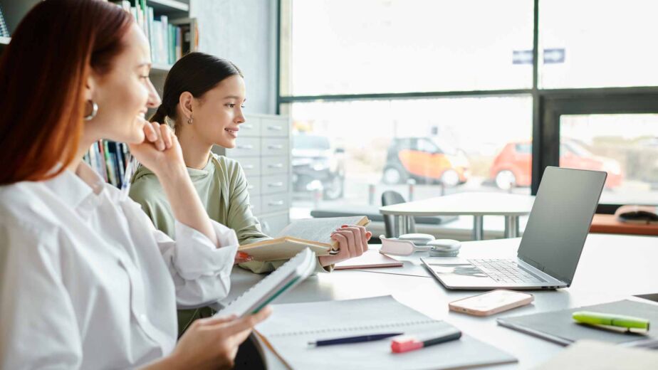Zwei Frauen arbeiten konzentriert mit Unterlagen und Laptop am Tisch – Erklärung zur Barrierefreiheit: Pflichtinhalte, Aufbau und häufige Fehler bei der BFSG- und BITV-2.0-konformen Konformitätserklärung