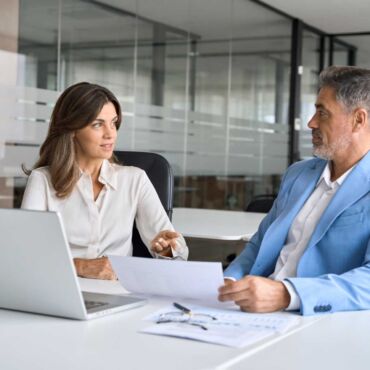 Zwei Personen im professionellen Beratungsgespräch mit Dokument und Laptop – EN 301 549: die technische Norm hinter BFSG und BITV 2.0 verstehen und in der Praxis anwenden nach WCAG 2.2