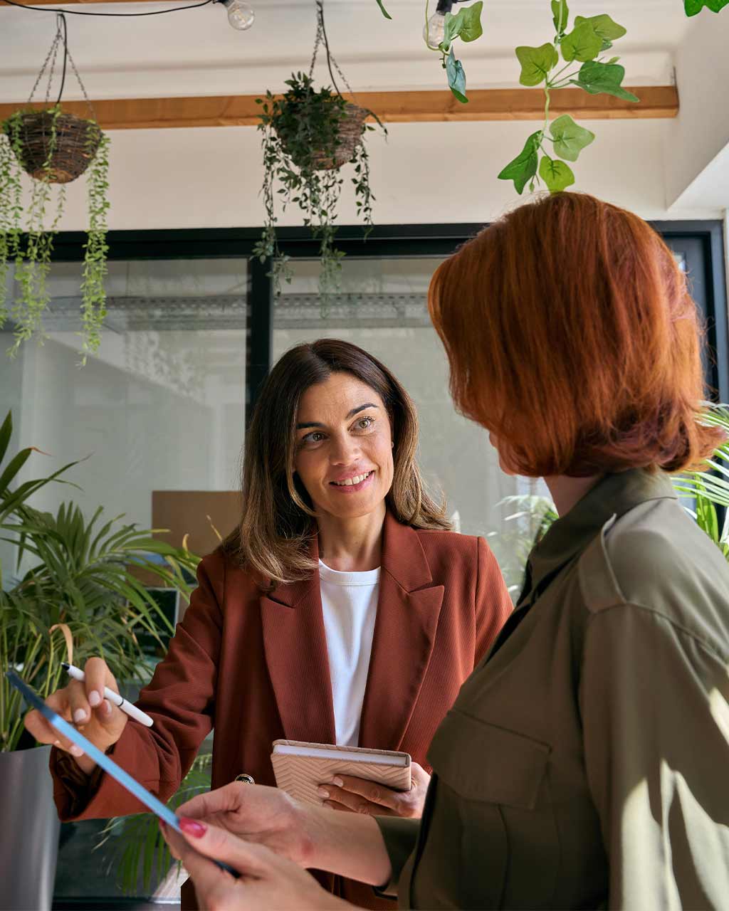 Zwei Frauen in Business-Kleidung tauschen sich mit Tablet und Stift aus – dauerhaftes Barrierefreiheits-Monitoring für Mittelstand, Agenturen und Enterprise-Organisationen nach BFSG und WCAG 2.2