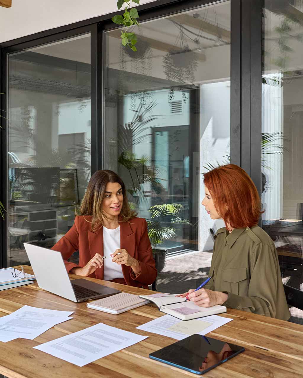 Zwei Frauen führen ein konzentriertes Beratungsgespräch mit Dokumenten und Laptop – vertraglicher BFSG-Abmahnschutz und Haftungsübernahme für Enterprise, Compliance-Verantwortliche und B2G-Organisationen nach WCAG 2.2