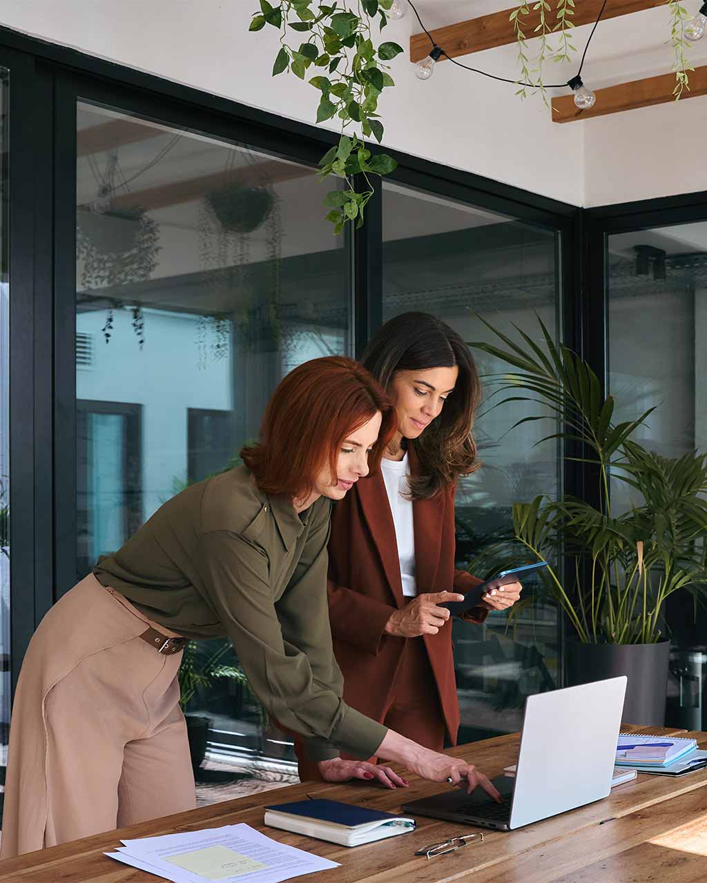Zwei Frauen in Business-Kleidung arbeiten gemeinsam an einem Laptop – BFSG-Tiefen-Audit mit IFDB-Zertifikat für Enterprise, Mittelstand und Digitalagenturen nach WCAG 2.2 und EN 301 549