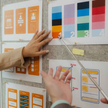 Hände ordnen UI-Wireframes und Farbkontrast-Karten an einer Pinnwand – WCAG 2.2 einfach erklärt: die wichtigsten Erfolgskriterien für kontrastreiche und zugängliche Webgestaltung nach BFSG