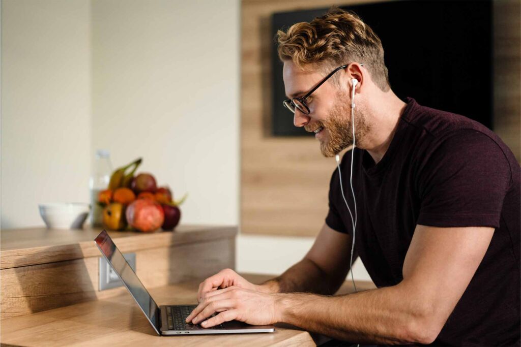 Mann mit Brille und Ohrhörern tippt konzentriert auf einem Laptop – Tastaturbedienung und Fokus-Management nach WCAG 2.2 für vollständig mausfreie Website-Navigation nach BFSG