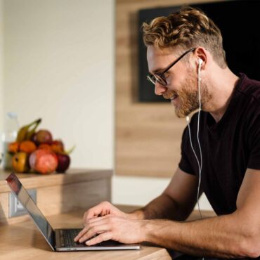 Mann mit Brille und Ohrhörern tippt konzentriert auf einem Laptop – Tastaturbedienung und Fokus-Management nach WCAG 2.2 für vollständig mausfreie Website-Navigation nach BFSG