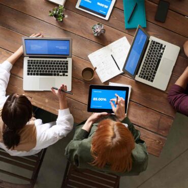 Team bespricht Strategie mit Laptops und Statistiken am Tisch – Barrierefreiheit-SEO: beide Disziplinen zusammen