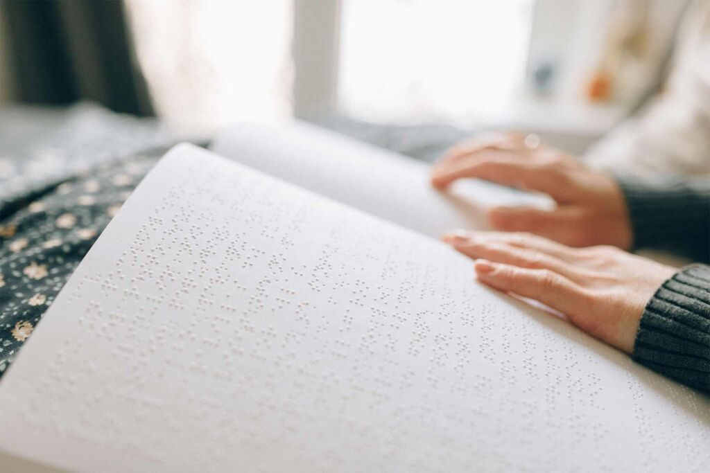 Hände ertasten Brailleschrift auf einer aufgeschlagenen Seite – wie blinde Menschen Inhalte lesen