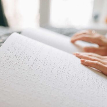 Hände ertasten Brailleschrift auf einer aufgeschlagenen Seite – wie blinde Menschen Inhalte lesen