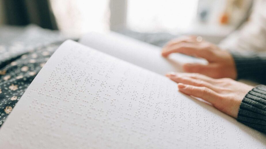 Hände ertasten Brailleschrift auf einer aufgeschlagenen Seite – wie blinde Menschen Inhalte lesen