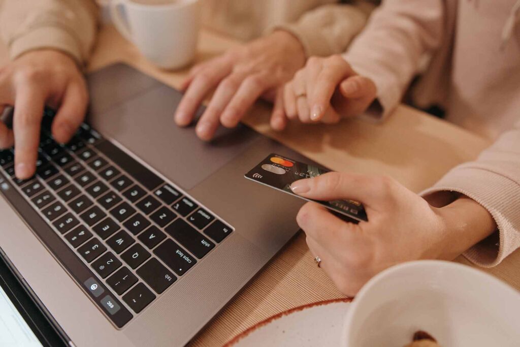 Hände am Laptop und eine Kreditkarte zur Bezahlung – barrierefreier Online-Shop im Checkout entscheidend