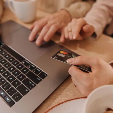 Hände am Laptop und eine Kreditkarte zur Bezahlung – barrierefreier Online-Shop im Checkout entscheidend