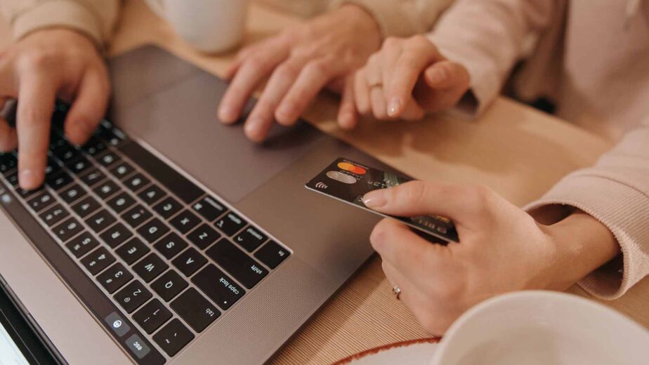Hände am Laptop und eine Kreditkarte zur Bezahlung – barrierefreier Online-Shop im Checkout entscheidend