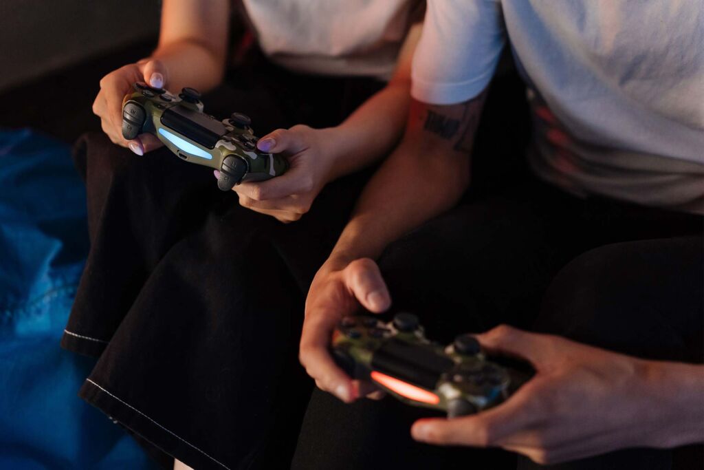 Personen spielen mit Controllern auf der Couch – barrierefreies Gaming: Spiele für alle spielbar machen