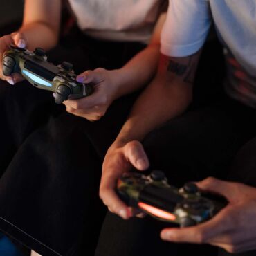 Personen spielen mit Controllern auf der Couch – barrierefreies Gaming: Spiele für alle spielbar machen