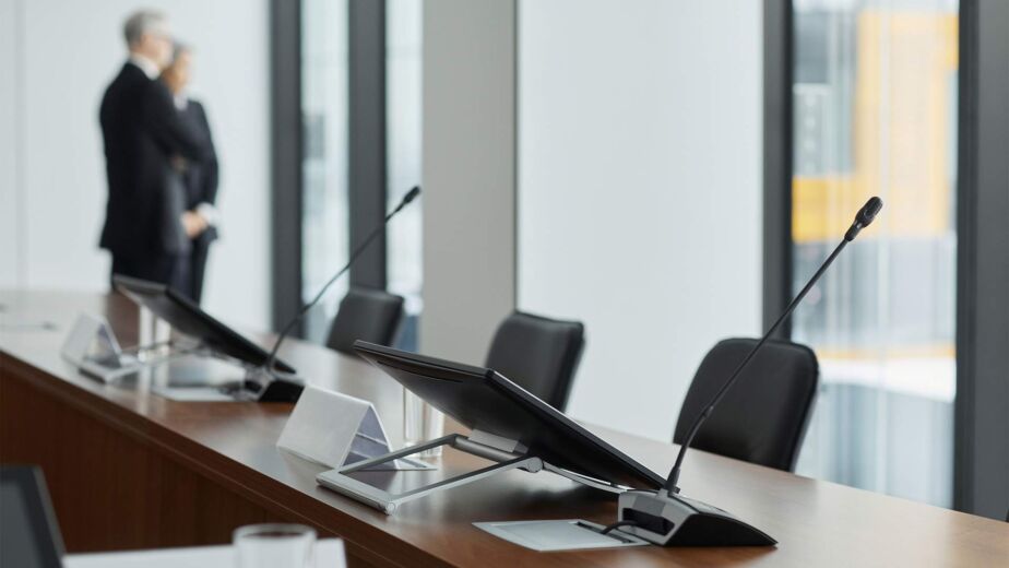 Konferenztisch mit Rednermikrofonen in Behördensaal – BGG, BITV, BFSG und EAA im Gesetzes-Überblick