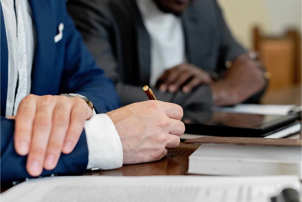 Hand hält Stift über Dokument im Geschäftstermin – Barrierefreiheit-Zertifizierung: welcher Nachweis zählt