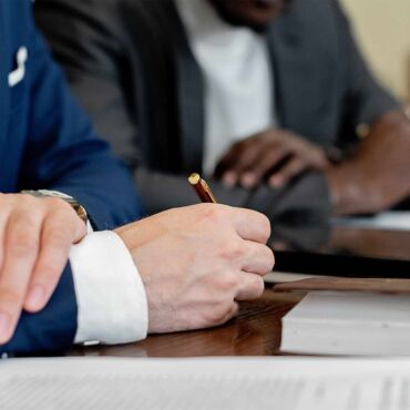 Hand hält Stift über Dokument im Geschäftstermin – Barrierefreiheit-Zertifizierung: welcher Nachweis zählt
