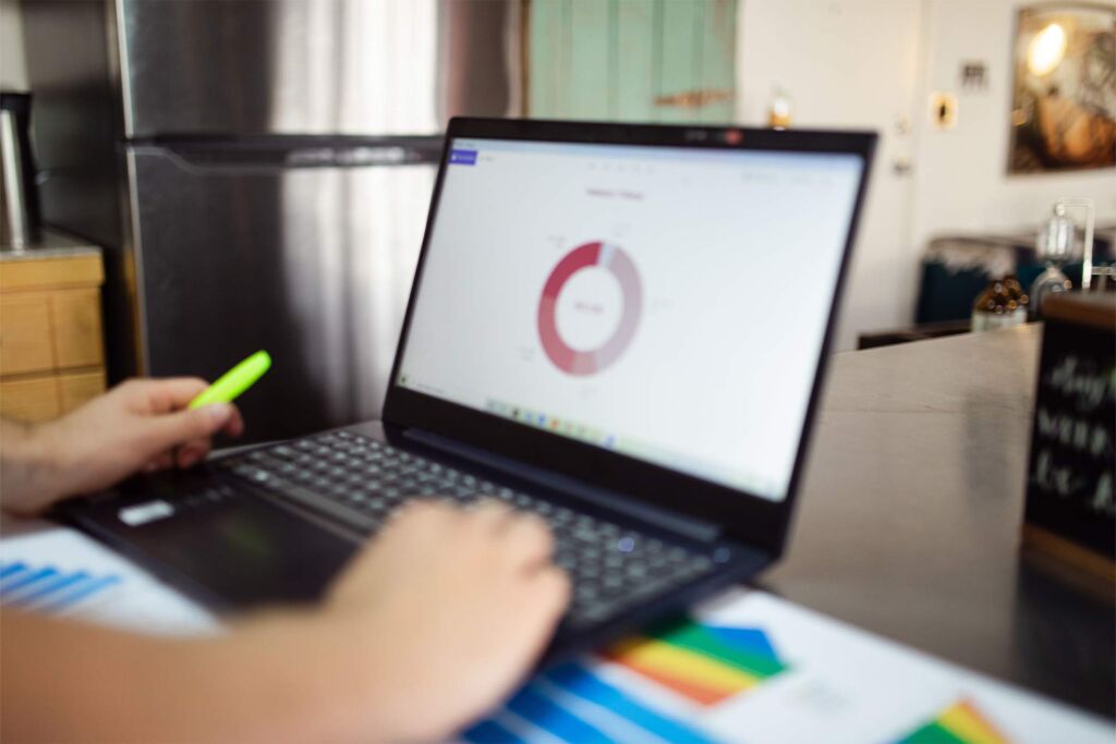 Person zeigt auf Ringdiagramm am Laptop neben bunten Balkengrafiken – Barrierefreiheits-Test: Tools im Vergleich