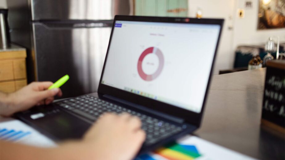 Person zeigt auf Ringdiagramm am Laptop neben bunten Balkengrafiken – Barrierefreiheits-Test: Tools im Vergleich