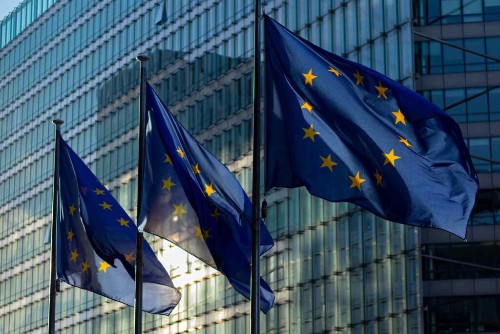 EU-Flaggen wehen vor Glasgebäude – European Accessibility Act: der EU-Rahmen für Barrierefreiheit