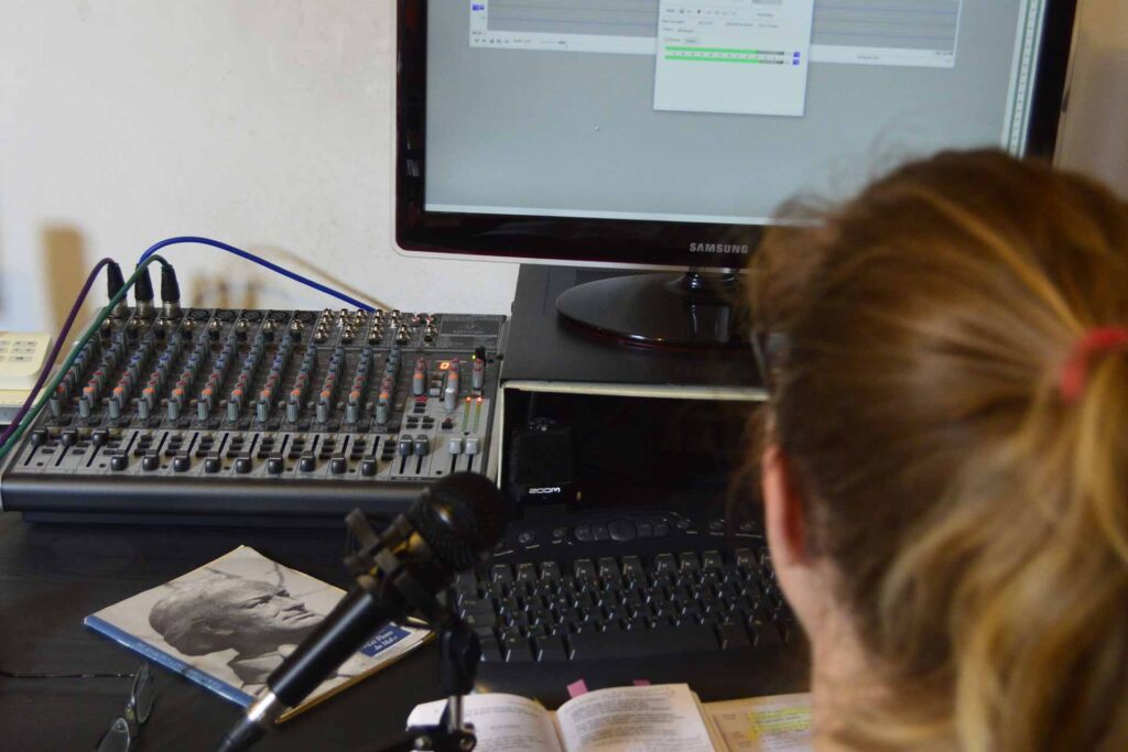 Person sitzt an Mischpult und Mikrofon vor Audio-Bildschirm – Screenreader: wie blinde Nutzer Websites bedienen
